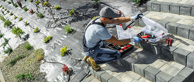 a male Landcape Horticulturalist working on installing a watering system in an outdoor garden area.